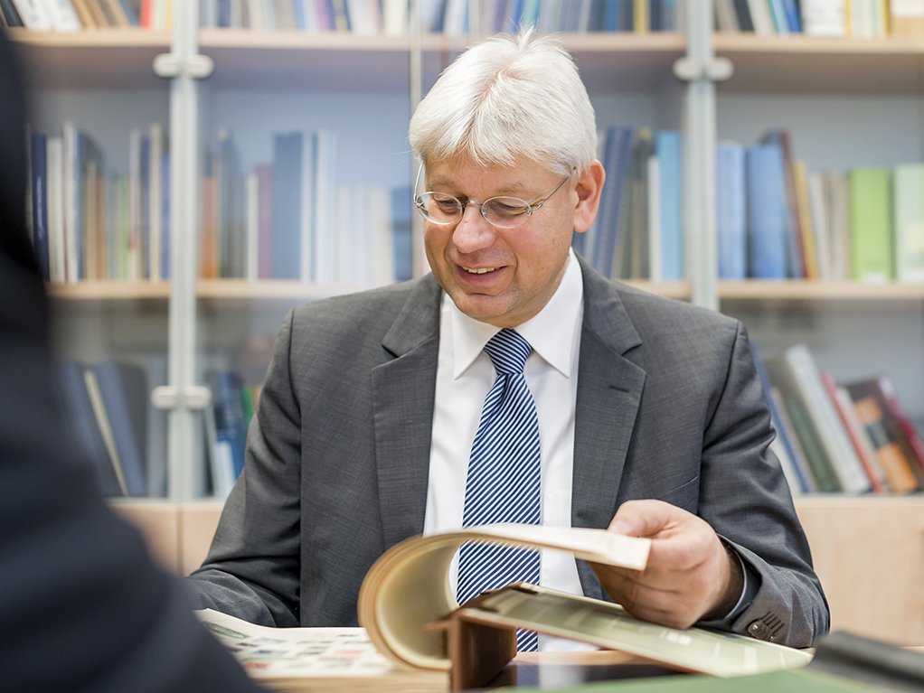 Christoph Gärtner blättert interessiert in einem Briefmarkenalbum und berät den Sammler
